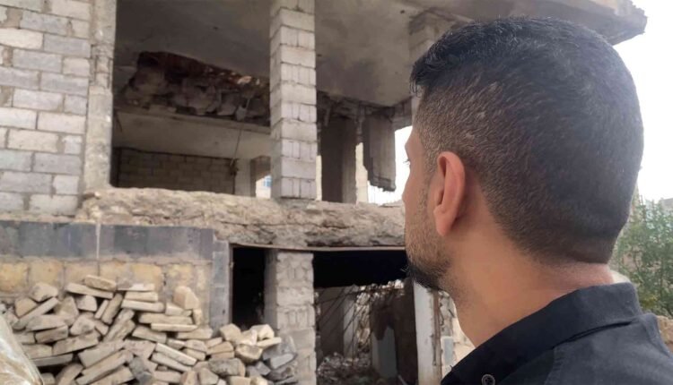 man looking at a destroyed house